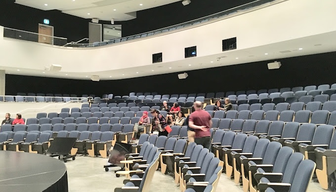 a collection of people sitting at a table with laptops in front of them